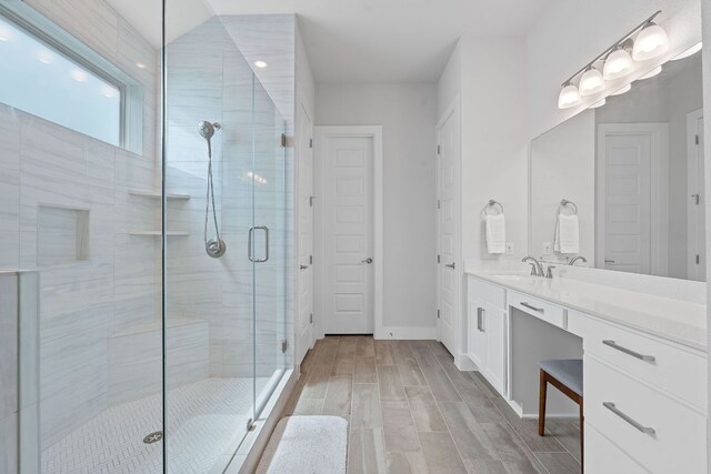 full bath featuring baseboards, vanity, wood finished floors, and a stall shower