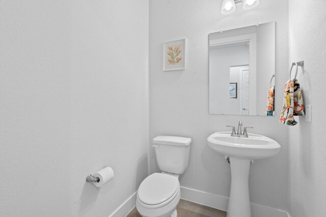 bathroom featuring toilet, baseboards, and a sink