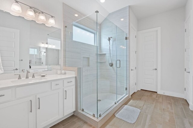 bathroom featuring wood finish floors, vanity, recessed lighting, and a stall shower
