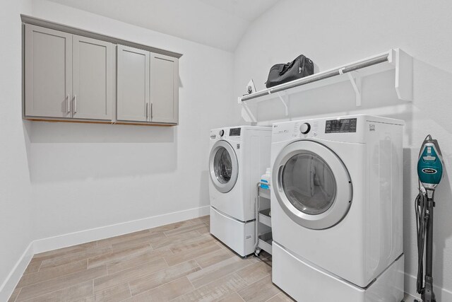 laundry area with cabinet space, light wood-type flooring, baseboards, and separate washer and dryer