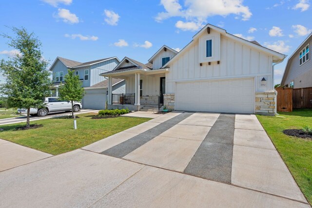 view of front of home with fence, board and batten siding, driveway, stone siding, and a front yard