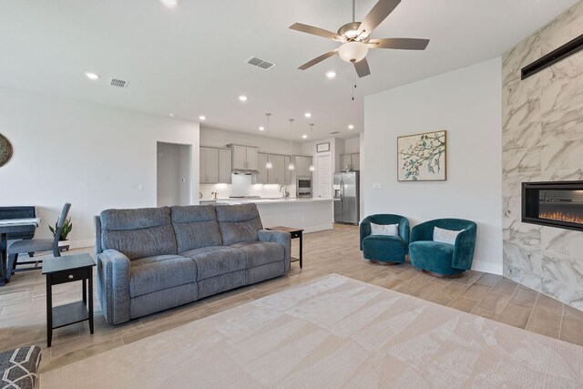 living area with a ceiling fan, wood tiled floor, a fireplace, visible vents, and recessed lighting