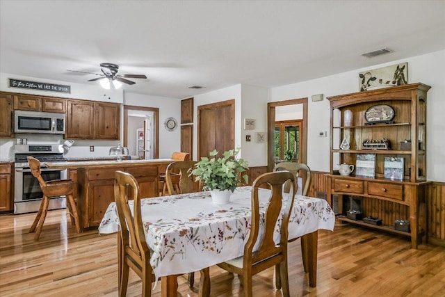 dining room featuring wainscoting, a ceiling fan, light wood finished floors, and visible vents