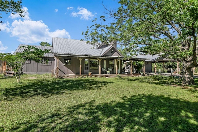 rear view of house featuring a porch, a lawn, and metal roof