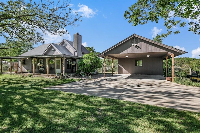 view of front of house with a chimney, driveway, covered porch, a carport, and a front yard