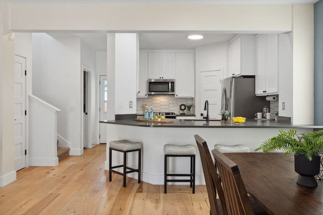7617 Carver Ave Unit 1, Austin, TX 78752 - kitchen featuring stainless steel appliances, tasteful backsplash, dark countertops, white cabinets, and a peninsula
