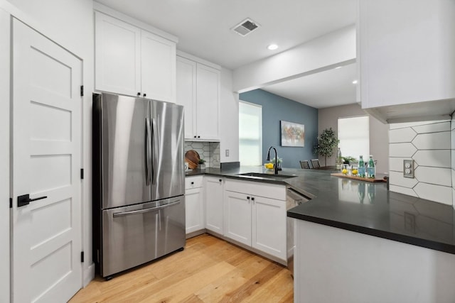 7617 Carver Ave Unit 1, Austin, TX 78752 - kitchen with stainless steel appliances, a sink, dark countertops, light wood-style flooring, and recessed lighting