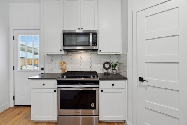 7617 Carver Ave Unit 1, Austin, TX 78752 - kitchen featuring stainless steel appliances, dark countertops, light wood-style floors, and white cabinetry