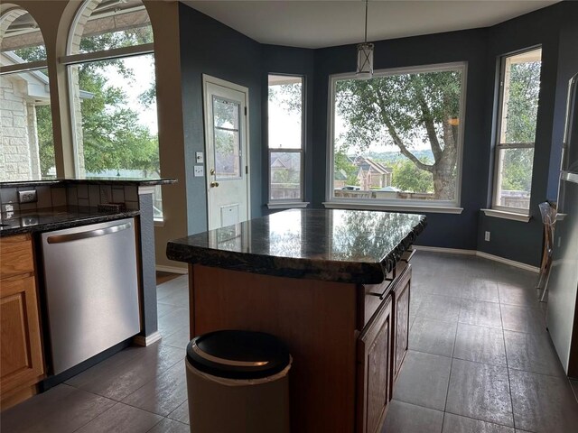 kitchen featuring dishwasher, baseboards, dark stone counters, pendant lighting, and dark tile patterned flooring
