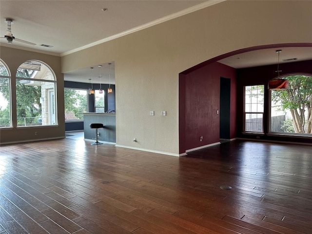 unfurnished living room with baseboards, visible vents, a wealth of natural light, and ornamental molding