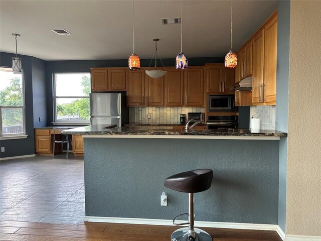 kitchen featuring tasteful backsplash, dark stone countertops, stainless steel appliances, baseboards, and visible vents