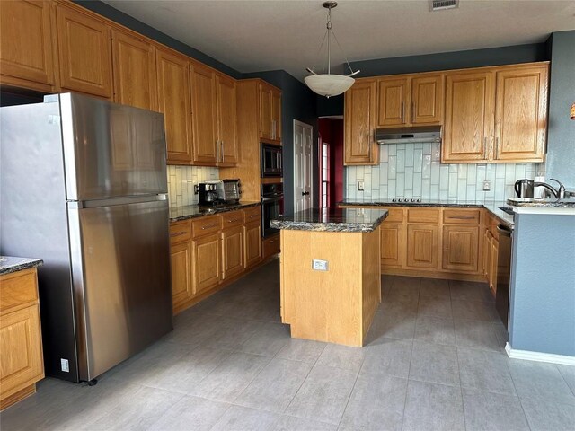 kitchen with under cabinet range hood, backsplash, a sink, a center island, and black appliances