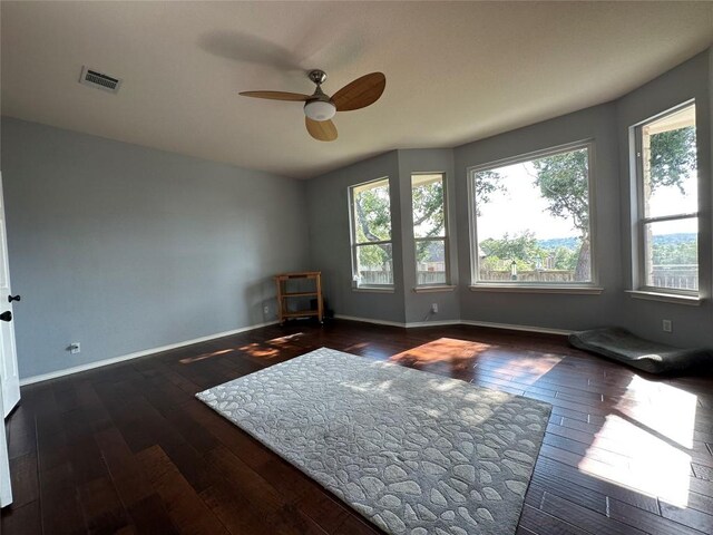 unfurnished room with hardwood / wood-style floors, visible vents, a ceiling fan, and baseboards