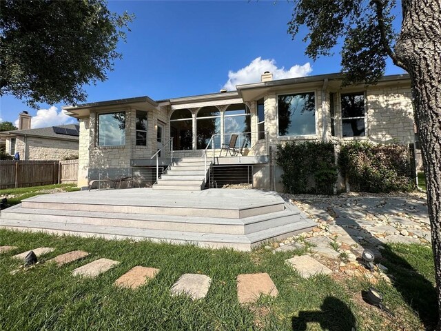 back of property with a chimney, a wooden deck, and fence