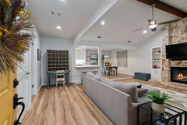 living room featuring light wood finished floors, a fireplace, a ceiling fan, visible vents, and baseboards