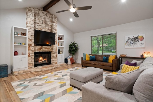 living area featuring a stone fireplace, wood finished floors, ceiling fan, beamed ceiling, and baseboards