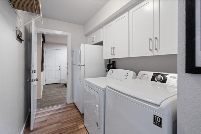 washroom with baseboards, cabinet space, wood finished floors, and washer and clothes dryer