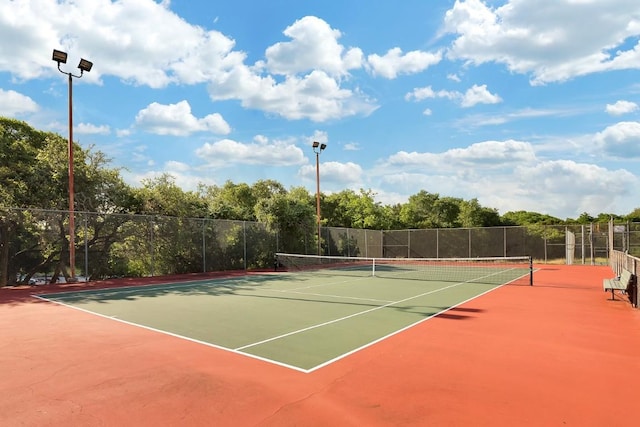 view of tennis court with community basketball court and fence
