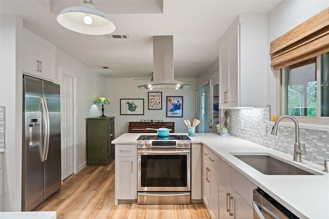 kitchen with a sink, island exhaust hood, stainless steel appliances, light countertops, and visible vents