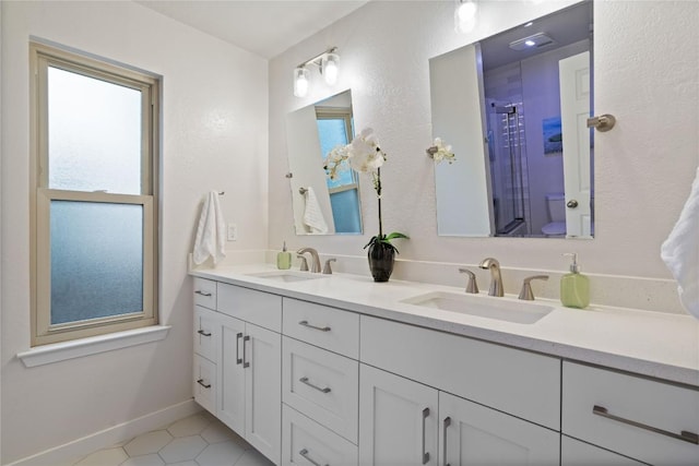 bathroom featuring double vanity, a healthy amount of sunlight, and a sink
