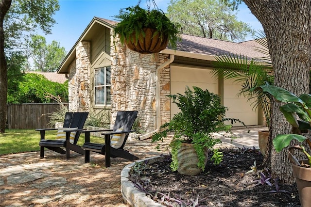 11311 Aloysia Dr, Austin, TX 78748 - view of home's exterior featuring stone siding, roof with shingles, a patio, and an attached garage