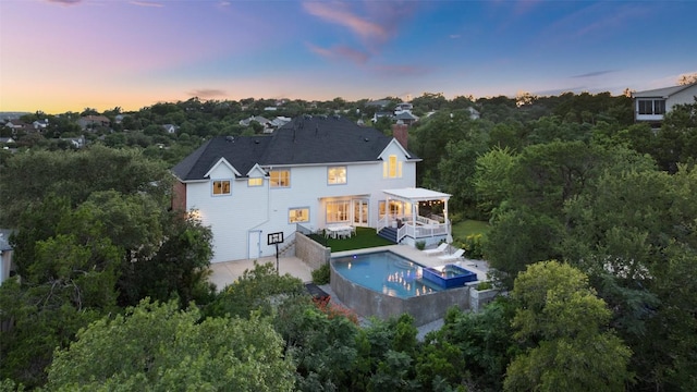 4014 Walnut Clay Dr, Austin, TX 78731 - back of house at dusk featuring an outdoor pool, a chimney, a deck, and an attached garage