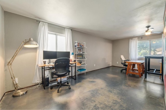 home office featuring ceiling fan, concrete flooring, a healthy amount of sunlight, and baseboards