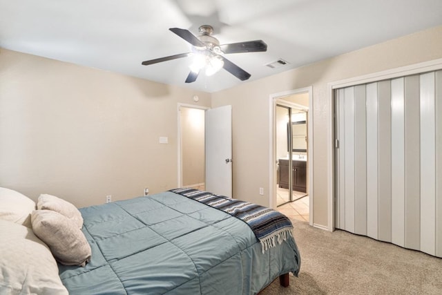 bedroom with light carpet, ensuite bathroom, visible vents, a ceiling fan, and a closet