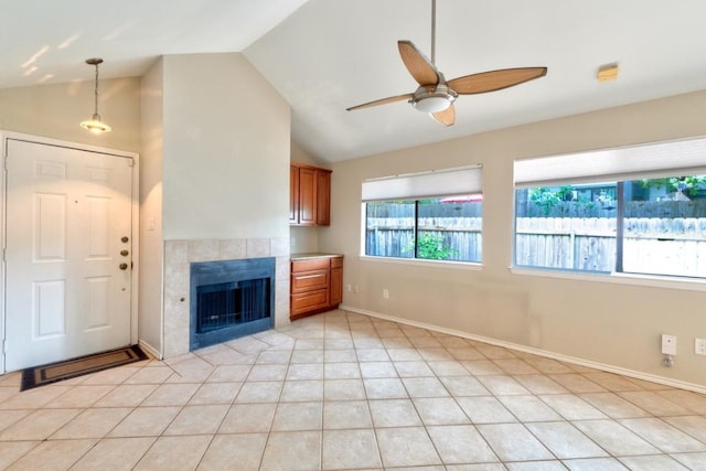 unfurnished living room featuring light tile patterned flooring, a tiled fireplace, ceiling fan, baseboards, and lofted ceiling
