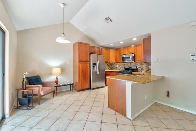 kitchen featuring brown cabinetry, a sink, a peninsula, tasteful backsplash, and appliances with stainless steel finishes