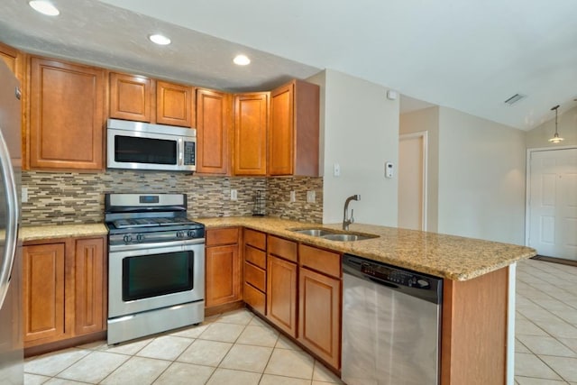 1411 Gracy Farms Ln Unit 122, Austin, TX 78758 - kitchen with appliances with stainless steel finishes, light tile patterned floors, brown cabinetry, decorative backsplash, and a peninsula