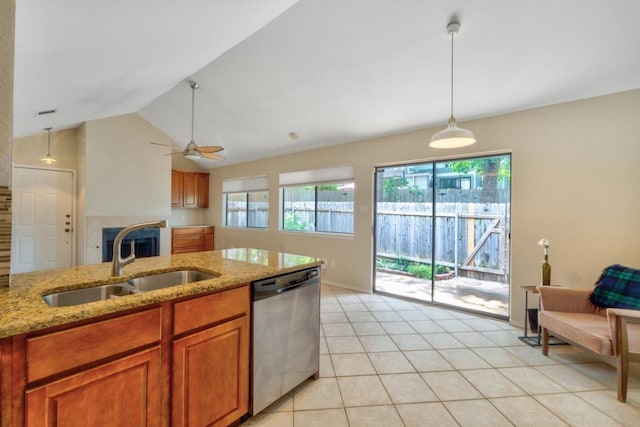kitchen with hanging light fixtures, a sink, brown cabinetry, dishwasher, and a tiled fireplace