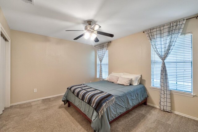 bedroom featuring baseboards, carpet floors, ceiling fan, and multiple windows