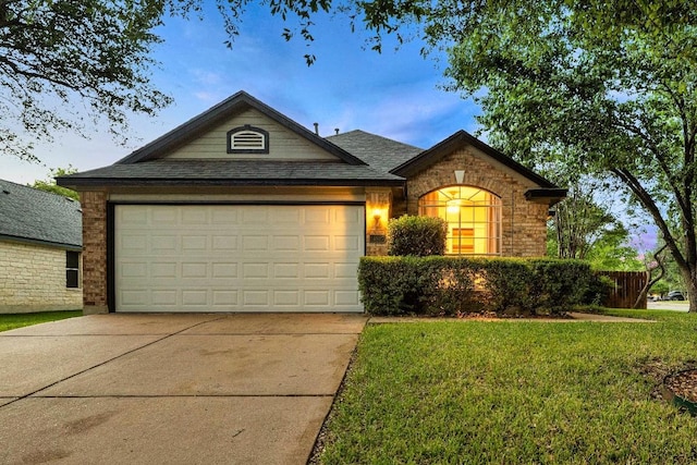 view of front facade with concrete driveway, brick siding, an attached garage, a shingled roof, and a front yard