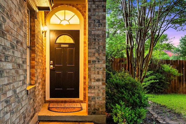 exterior entry at dusk with fence and brick siding