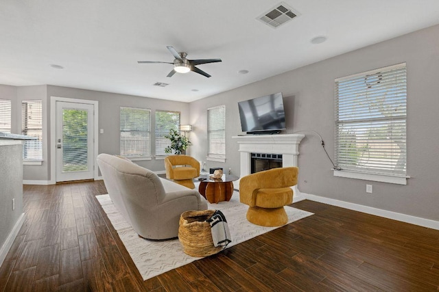 living area featuring baseboards, a ceiling fan, visible vents, and a fireplace