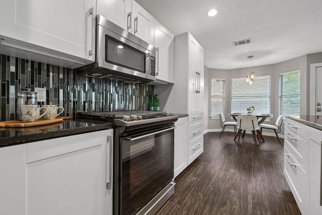 kitchen with stainless steel microwave, baseboards, visible vents, black range with gas stovetop, and dark wood-type flooring