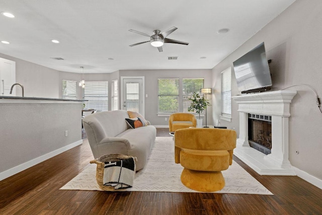 living room with a fireplace with raised hearth, ceiling fan, baseboards, visible vents, and recessed lighting