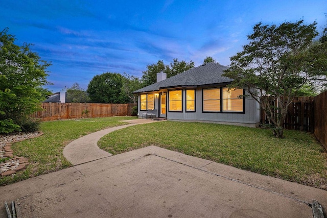 rear view of property with a lawn, a chimney, a patio, and a fenced backyard