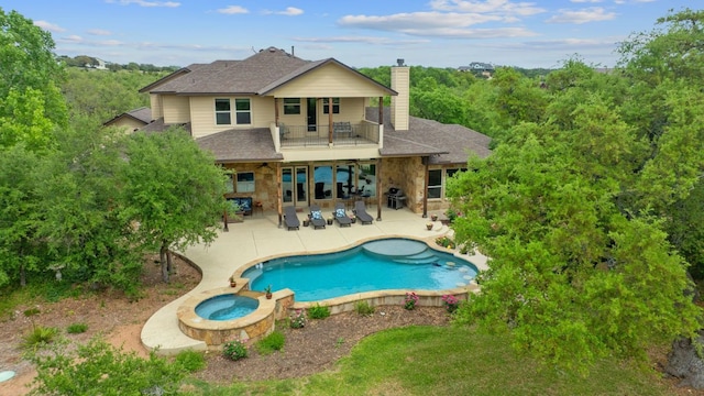 rear view of house with a balcony, a chimney, a ceiling fan, a shingled roof, and a patio