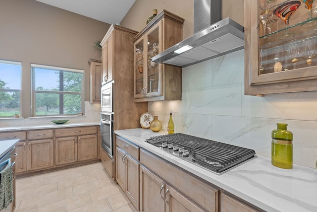 kitchen with wall chimney exhaust hood, stainless steel appliances, and decorative backsplash