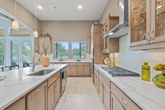 kitchen featuring a sink, visible vents, backsplash, wall chimney range hood, and appliances with stainless steel finishes