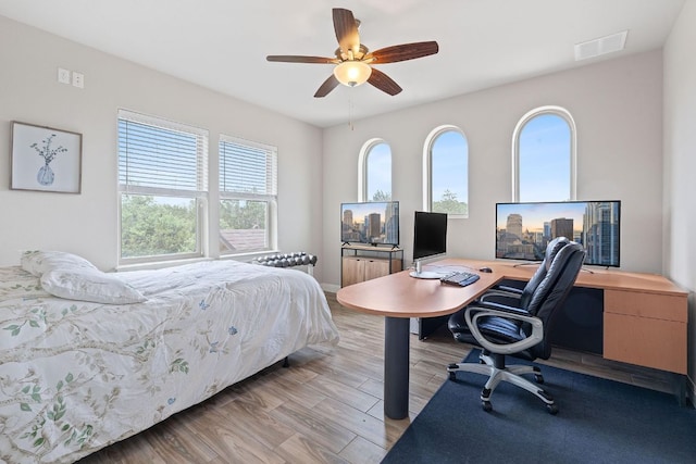 bedroom with ceiling fan, wood finished floors, multiple windows, and visible vents