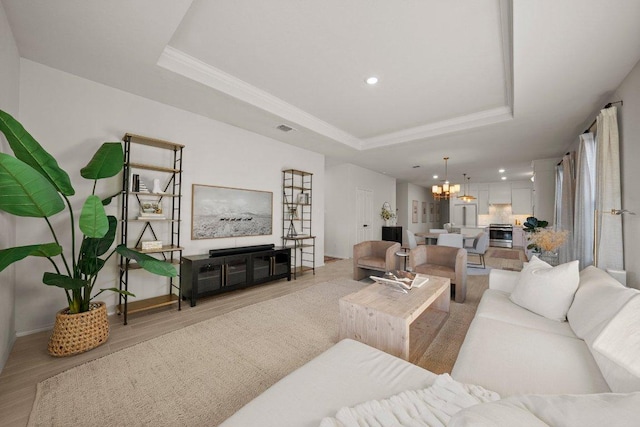 370 Grace Lilly Dr, Buda, TX 78610 - living room with a tray ceiling, light wood finished floors, a chandelier, recessed lighting, and crown molding