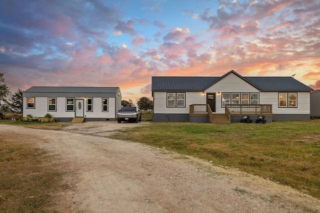 view of front of house featuring dirt driveway, a lawn, and metal roof