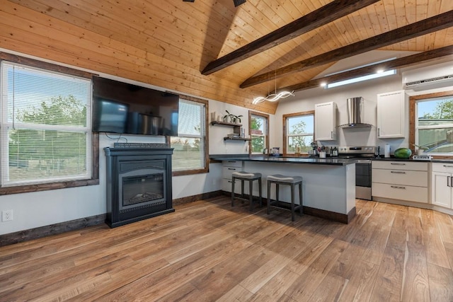 kitchen featuring dark countertops, wall chimney range hood, a wall unit AC, stainless steel electric range, and white cabinetry