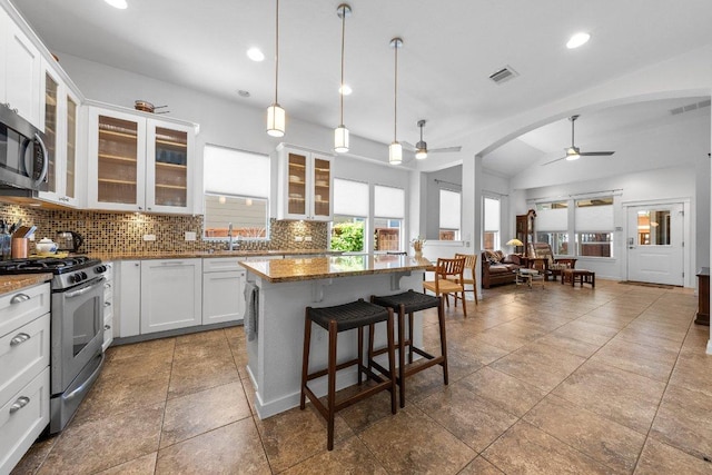kitchen featuring stainless steel appliances, vaulted ceiling, recessed lighting, decorative backsplash, and ceiling fan