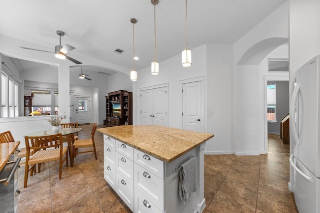 kitchen featuring a wealth of natural light, ceiling fan, arched walkways, and freestanding refrigerator