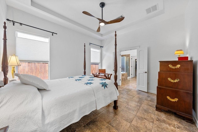 bedroom featuring visible vents, stone finish flooring, a raised ceiling, and multiple windows