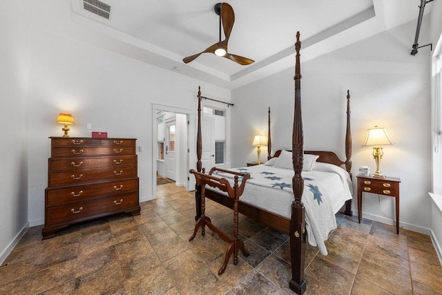 bedroom featuring baseboards, stone finish floor, visible vents, and a raised ceiling